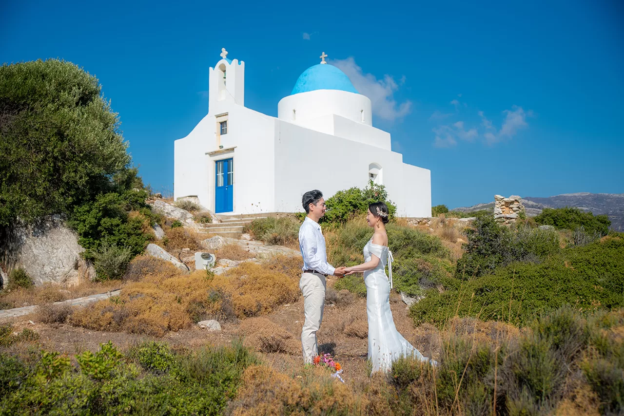 Just married couple holding hands in front of church in Naxos, captured by Naxos Photographer