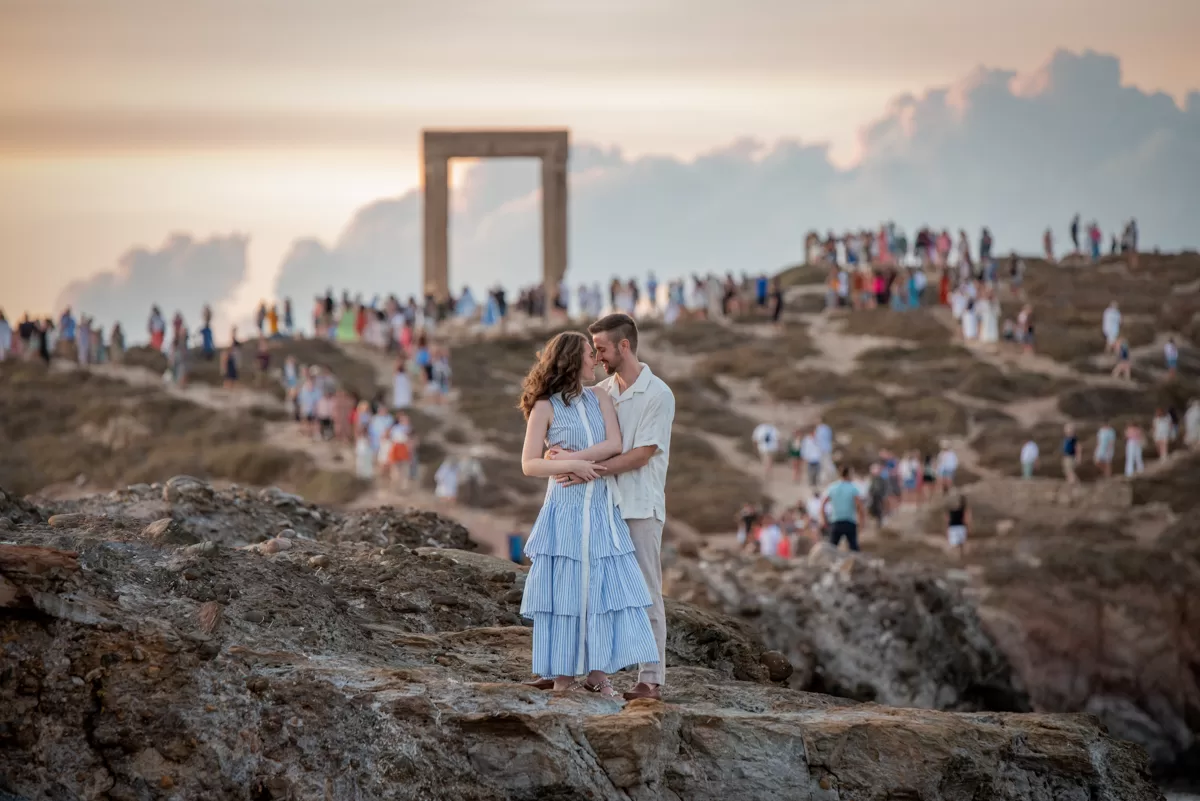 Couple romantically hugging on a rock with the Portara in the background, in Naxos, captured by a Naxos photographer